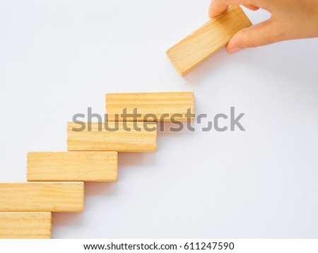 Concept of building success foundation. Women hand put wooden blocks in the shape of a staircase