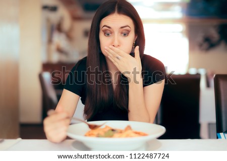 Woman Feeling Sick While Eating Bad Food in a Restaurant. Dinner customer having a bad experience feeling sick