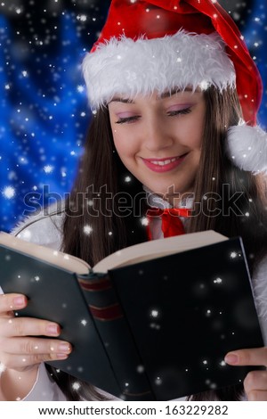 Christmas Girl Reading - Beautiful girl holding a hard cover book or album with snow falling around her.