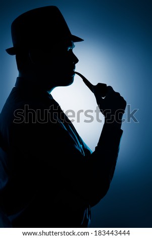 Silhouette of Man Smoking Pipe on a Spotlight Background - Silhouette of a man wearing a hat and smoking pipe