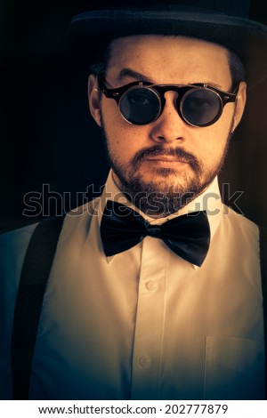 Man with Top Hat and Steampunk Glasses Retro Portrait - Gentleman portrait, young bearded man wearing steampunk glasses, bowtie and top hat