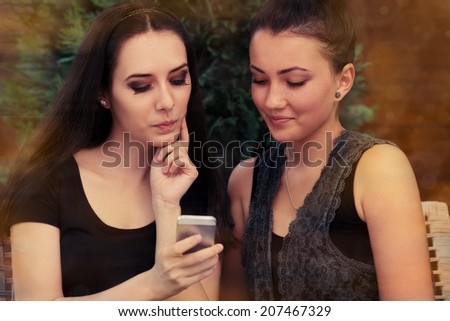 Young Women Looking at Smart Phone Screen - Two girls looking at a smart phone screen, reading