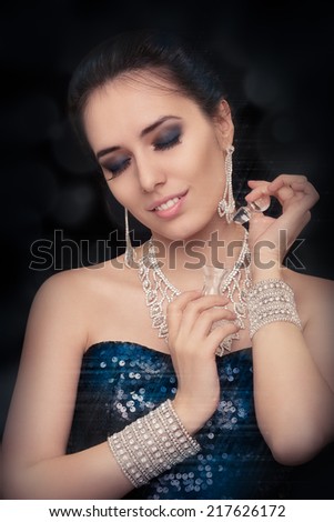 Retro glamour woman holding vintage perfume bottle wearing silver accessories - Glamorous portrait of a beautiful young woman preparing for party using a vintage perfume bottle