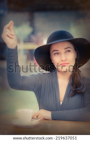 Young Woman Calling a Waiter - Young woman wearing a broad hat snaps her fingers to call the waiting staff