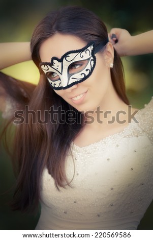 Young Woman Putting on a Mask - Portrait of a woman preparing for a masquerade bal