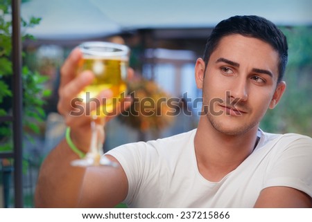 Young Man Rising a Glass in a Bar- Portrait of a handsome man drinking and making a toast  in a restaurant pub