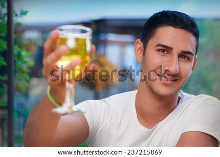 Young Man Rising a Glass in a Bar- Portrait of a handsome man drinking and making a toast  in a restaurant pub
