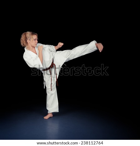 Young Karate Woman in a White Kimono Kicking - Portrait of a young beautiful martial arts girl in kimono exercising