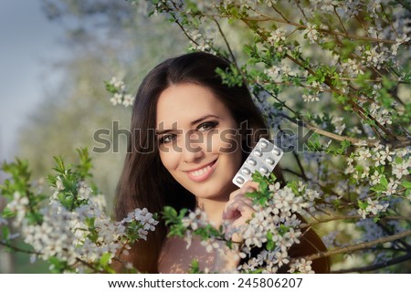 Woman with Allergy Holding Anti Allergic Pills in Spring Blooming Decor - Portrait of an allergic woman surrounded by seasonal flowers holding treatment