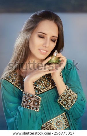 Young Woman Holding Perfume Bottle in Seaside Landscape - Portrait of a glamorous woman with retro fragrance recipient in beautiful seascape