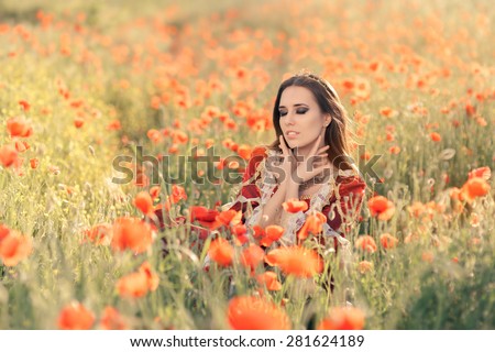 Beautiful Princess in a Field of Poppies - Portrait of a happy beautiful queen in red royal dress in nature