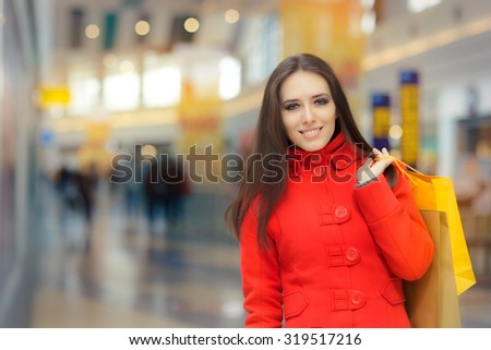Happy Girl in a Red Coat Shopping in a Mall - Smiling fashion woman holding shopping bags in a big mall