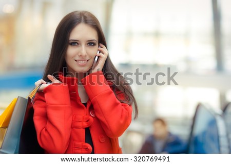 Shopping Mall Girl in a Red Coat Talking on Smartphone - Smiling woman with shopping bags in a mall talking on the phone