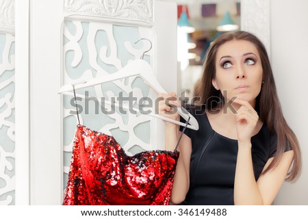 Astonished Girl Trying on Red Party Dress in Dressing Room - Funny fashion with a clothes hanger deciding what to wear