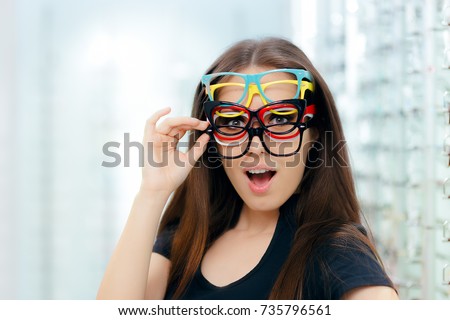 Funny Woman Trying Many Eyeglasses Frames in Optical Store\
Happy girl wearing lots of colorful spectacles at the same time