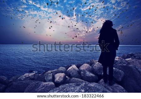 woman standing on the rocks watching sea sunset ,dramatic view,woman on the edge ,woman silhouette unusual