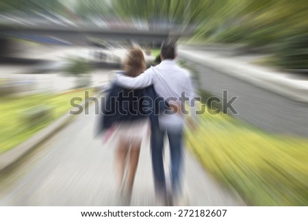 Young happy couple walking in the park, back view,blurry unfocused background,love and happiness ,couple in love walking