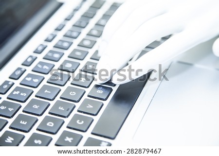 Close-up of white doll hands typing on laptop keyboard