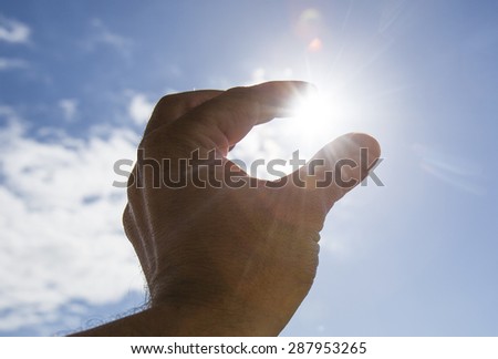 Hand to sun,sun rays passing through fingers,holding sun