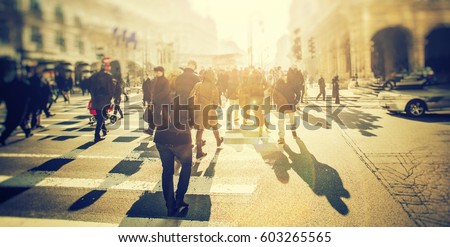 Crowd of anonymous people walking on sunset in the city streets