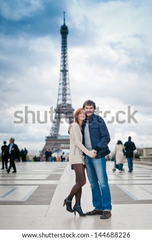Lovers look at camera in Paris with the Eiffel Tower in the Background
