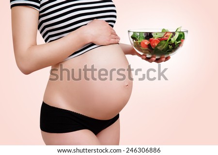 Healthy nutrition and pregnancy. Close-up pregnant woman\'s belly and vegetable salad