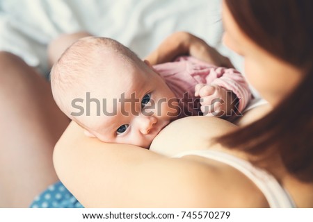 Baby eating mother\'s milk. Mother breastfeeding baby. Beautiful mom breast feeding her newborn child. Young woman nursing and feeding baby. Concept of lactation infant.