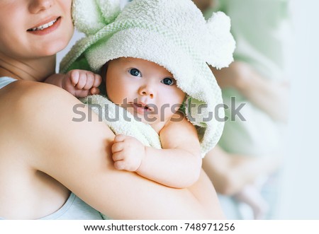 Mom hugs her little cutest baby after bath with towel on head. Child caring routine. Family life. Mother and baby.