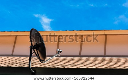 black small satellite on brown roof at blue sky