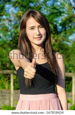 close up face asia young woman and make hand thumbs up at outdoor on public natural park