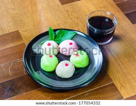 color mo chi cakes on black dish with black tea in glass on brown wood parquet floor ground