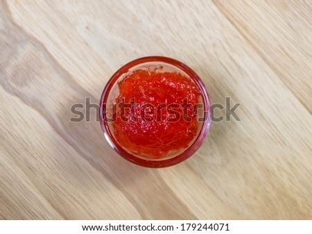 strawberry jam in small dishware on wood pattern background