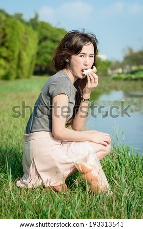 portrait asia Young girl happy and eat bread desert for picnic resting at outdoor garden