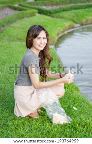 portrait asia Young girl happy and feeding for fish in water lake natural at outdoor garden