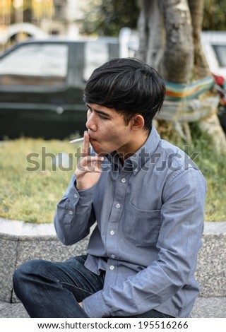 portrait young asia  man relax and smoking at outdoor summer