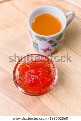 strawberry jam in  dishware and orange water drink on wood pattern background