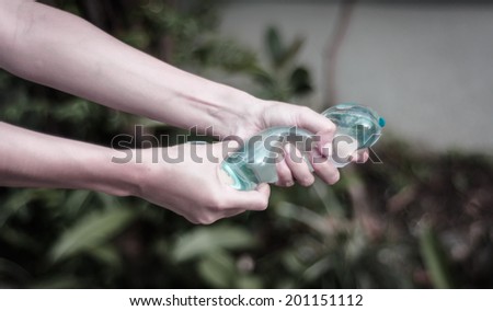 girl hand holding water balloon with retro filter at blur natural background