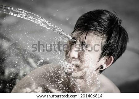 asia young man washing him face and Water splash with retro filter. at outdoor blur background