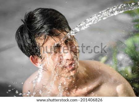 asia young man washing him face with Water splash. at outdoor blur background