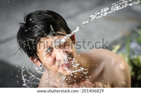 asia young man washing him face with Water splash. at outdoor blur background