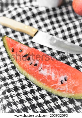 watermelon fruit and kitchen knife on plaid fabric background at outdoor