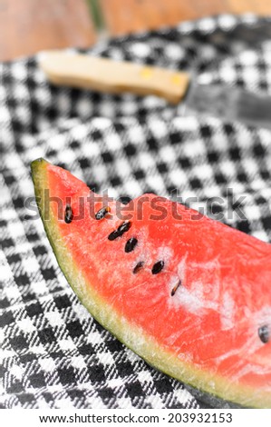 watermelon fruit and kitchen knife on plaid fabric background at outdoor