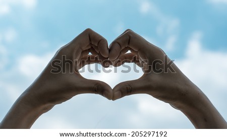 asian Girl hand in heart form love sign on blue sky background