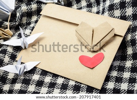 letter brown paper envelope with red heart and paper bird at plaid fabric background