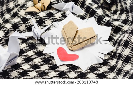 heart paper symbol and paper bird on a plaid textile background with retro filter