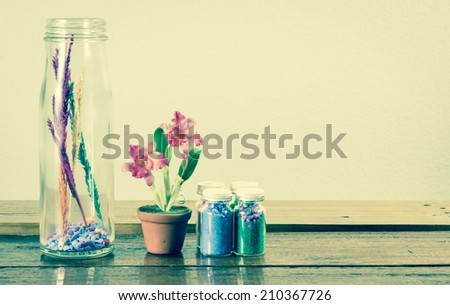 color sand in glass bottle deco and flower on wooden table with retro filter