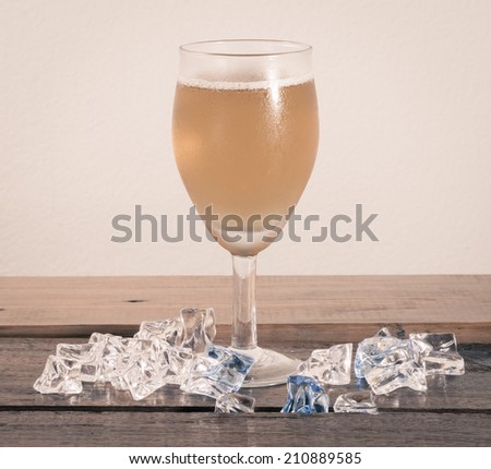 beer in glass and ice cube on wood table at concrete background with retro filter