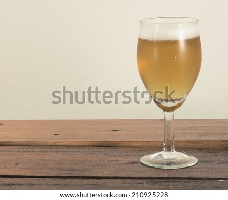 beer in wine glass on wood table at concrete background with retro filter