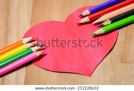 old Color pencils with heart paper sign on wood pattern background