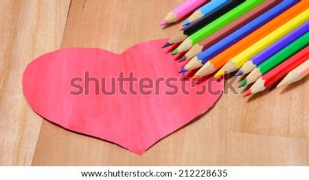 old Color pencils with heart paper sign on wood pattern background
